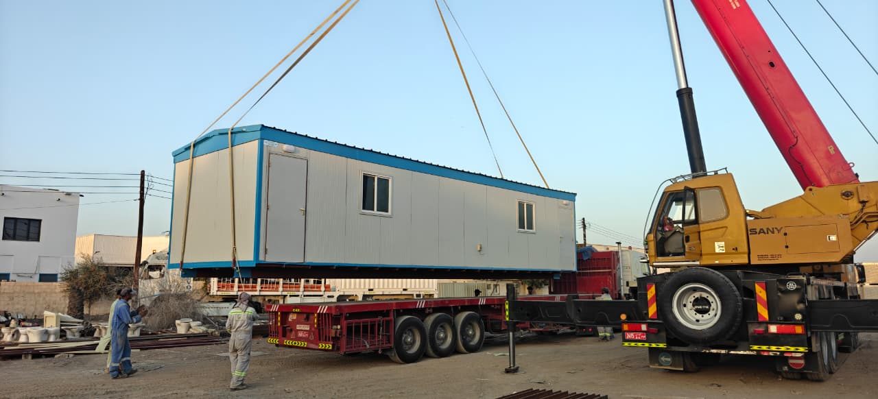 Crane lifting a portacabin onto a transport trailer